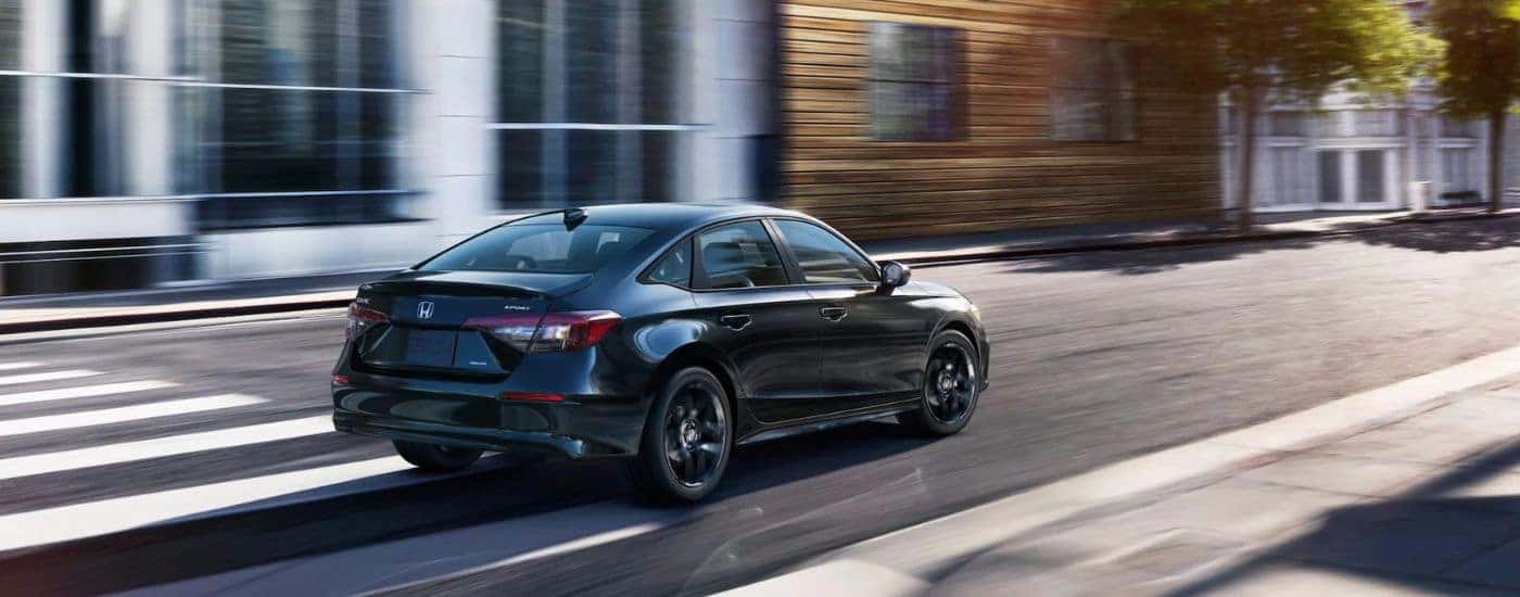 Black 2025 Honda Civic Hybrid Sport driving through a crosswalk