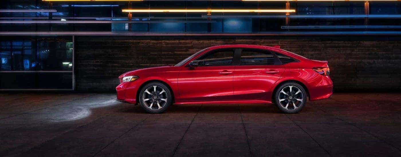 Side profile of a red 2026 Honda Civic Hybrid parked at night