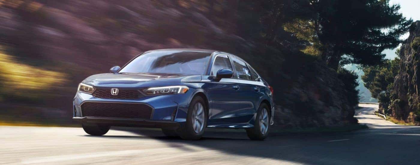 Blue 2026 Honda Civic Hybrid LX driving on a bendy road