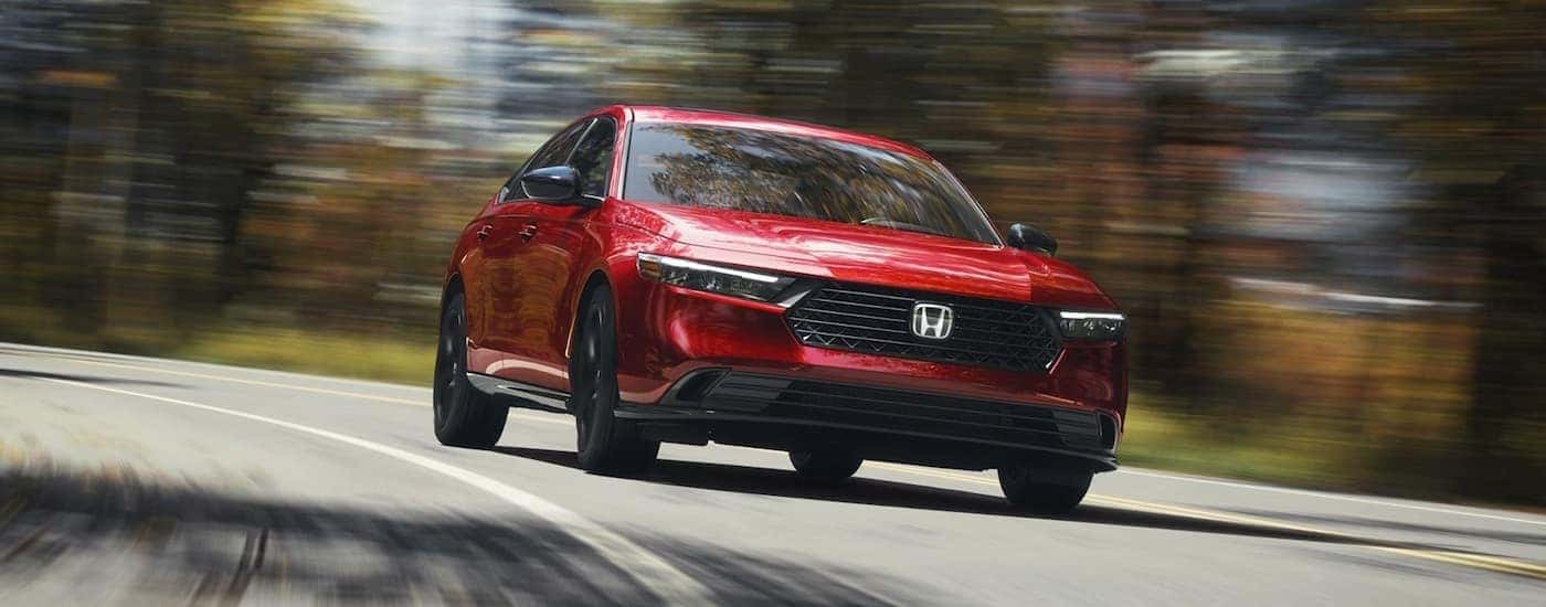 Red 2026 Honda Accord driving on a winding road corner