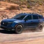 Blue 2026 Honda CR-V driving on a dusty dirt road