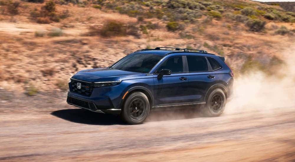 Blue 2026 Honda CR-V driving on a dusty dirt road