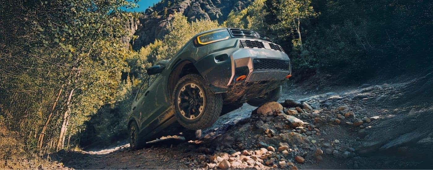Green 2026 Honda Passport TrailSport crawling up rocks.