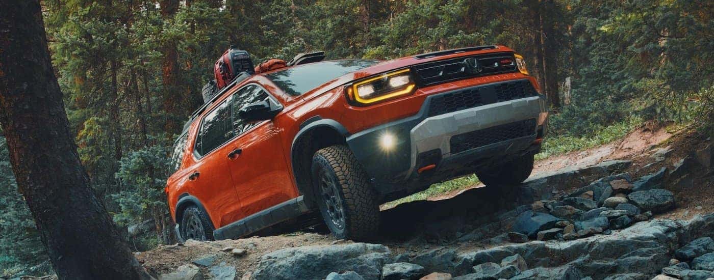 Orange 2026 Honda Passport TrailSport Elite climbing a mountain.