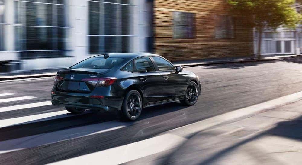 A black 2026 Honda Civic Hybrid driving in a city.
