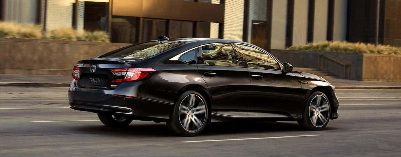 Black 2021 Honda Accord Hybrid driving down a street.