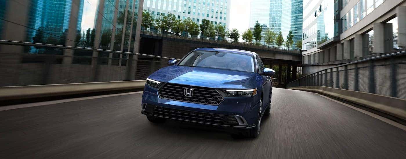 Blue 2023 Honda Accord Touring Hybrid driving across a bridge.