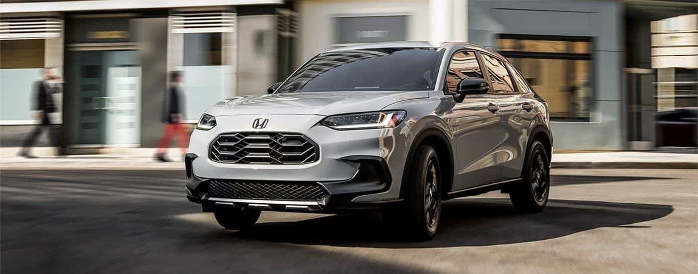 A silver 2023 Honda HR-V parked in front of blurred buildings.