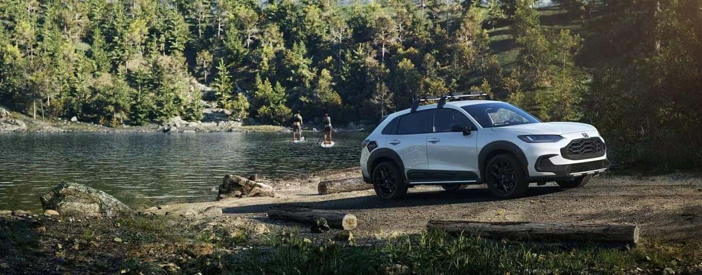 A white 2023 Honda HR-V parked in front of a lake.