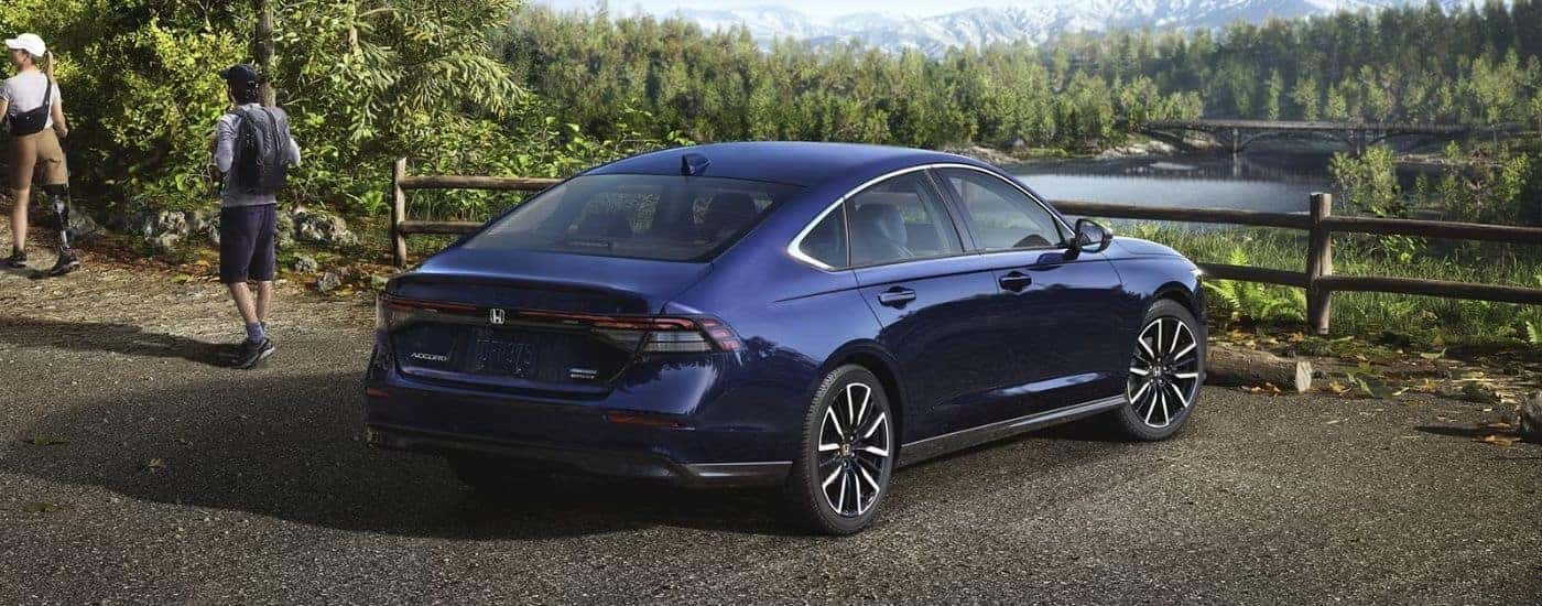 Rear view of a blue 2026 Honda Accord parked in front of a fence and water.