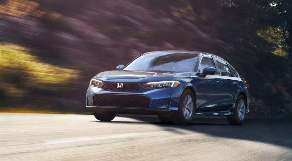 Blue 2026 Honda Civic driving down a road.