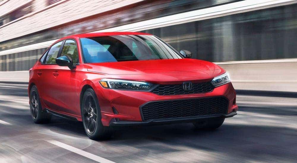 Red 2026 Honda Civic driving down a city street.