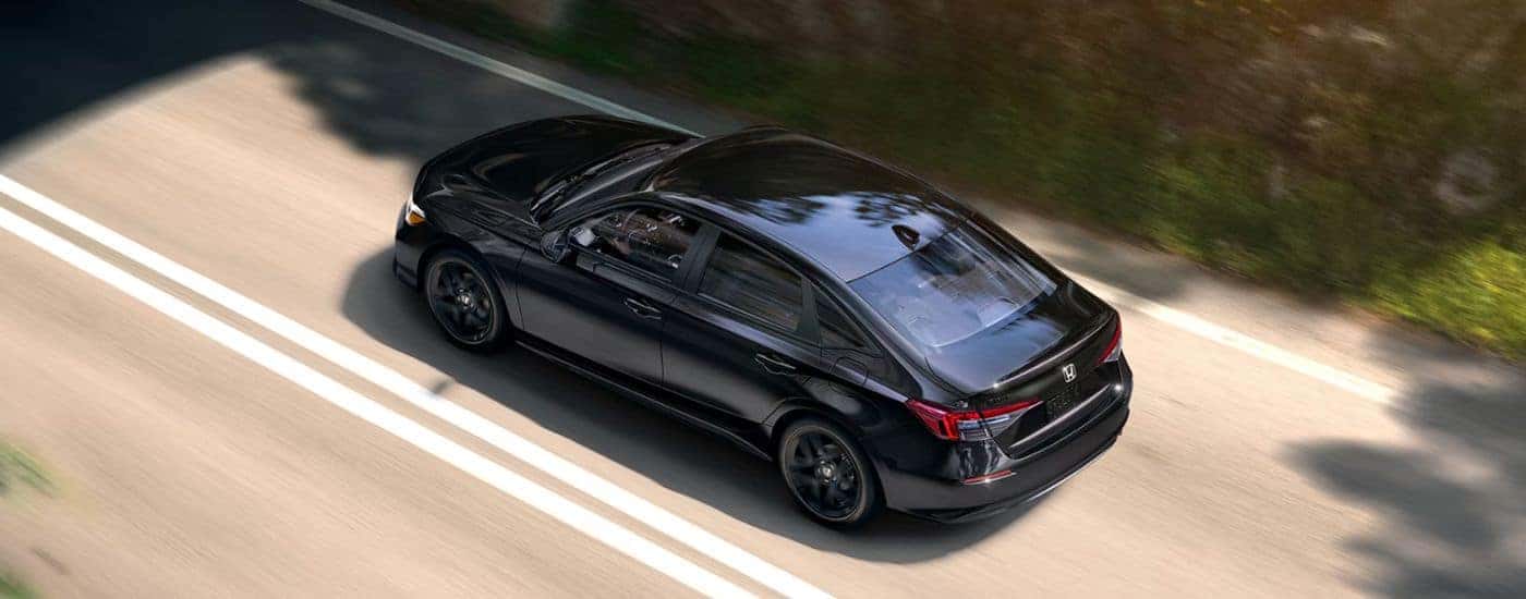 A black 2026 Honda Civic Sport driving down a road.