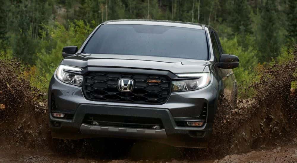 A gray 2026 Honda Ridgeline TrailSport shown driving in mud.