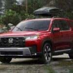A red 2026 Honda Pilot Elite shown driving in the rain.