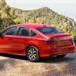 A red 2026 Honda Civic Sedan parked by a scenic view and two people.