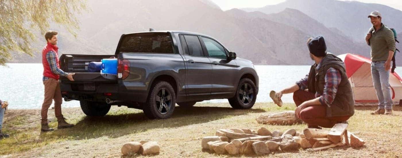 A silver 2026 Honda Ridgeline TrailSport parked at a campsite.