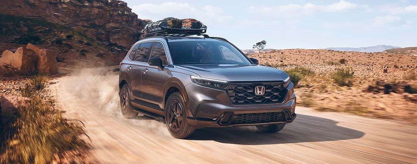 Grey 2023 Honda CR-V Sport on a trail with luggage on the rack.s