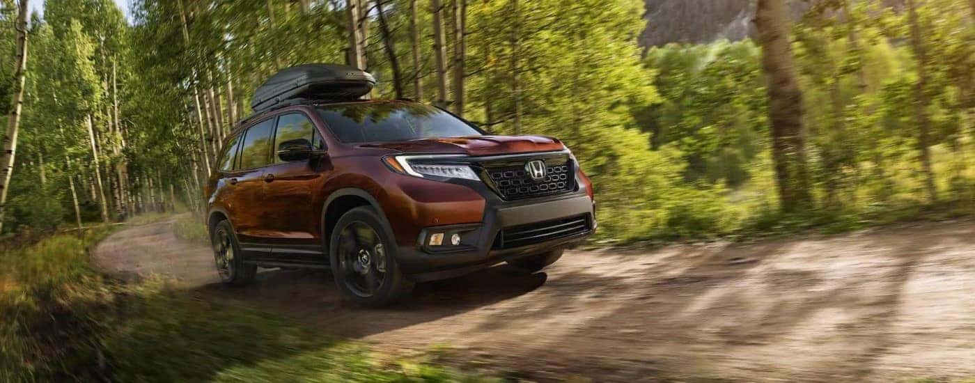 A dark red 2020 Honda Passport driving off road.