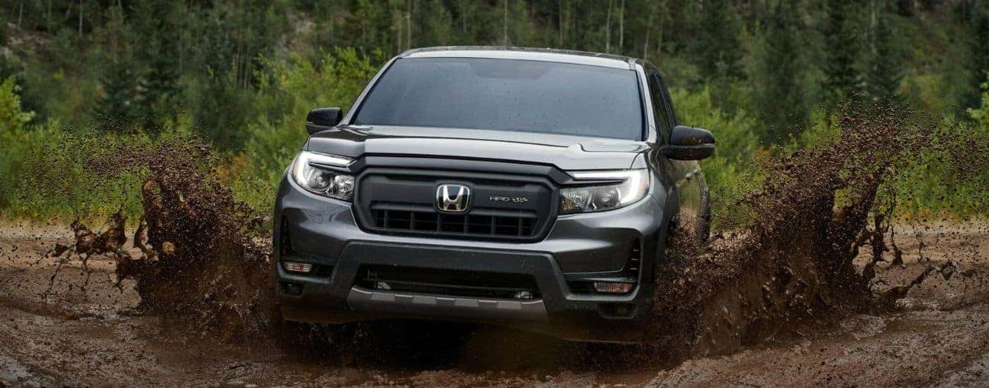 A gray 2024 Honda Ridgeline HPD+ driving in mud.