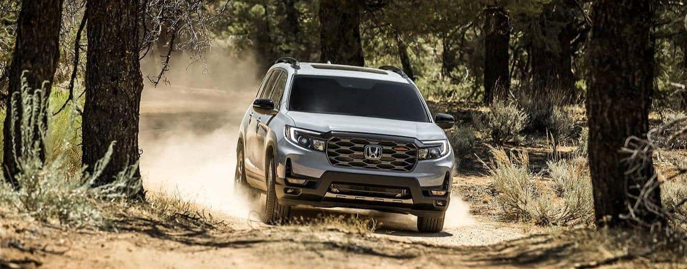 A silver 2023 Honda Passport TrailSport driving off-road.