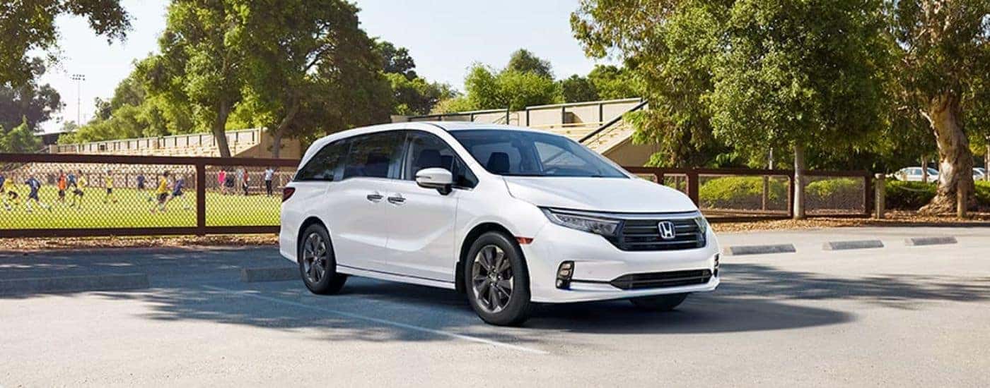 A white 2023 Honda Odyssey parked by a field.