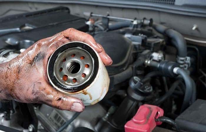 An auto mechanic shows an old, dirty oil filter