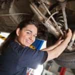 Female mechanic working on a car and smiling
