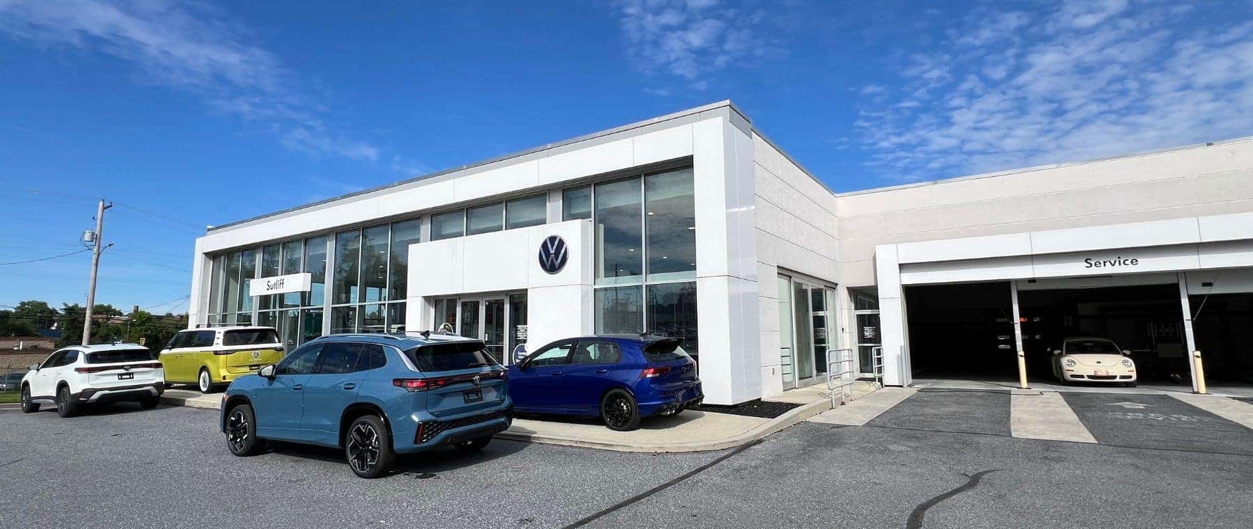 Two people outside a restaurant talking next to a blue Volkswagen SUV 