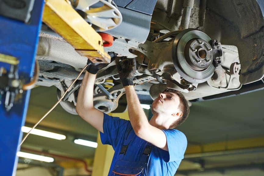 garage auto mechanic repairman checking car suspension during automobile maintenance at repair service station