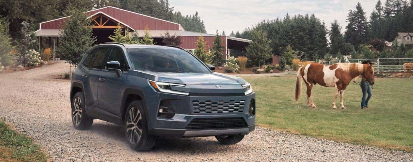 Blue 2026 Toyota RAV4 on a farm with a horse.
