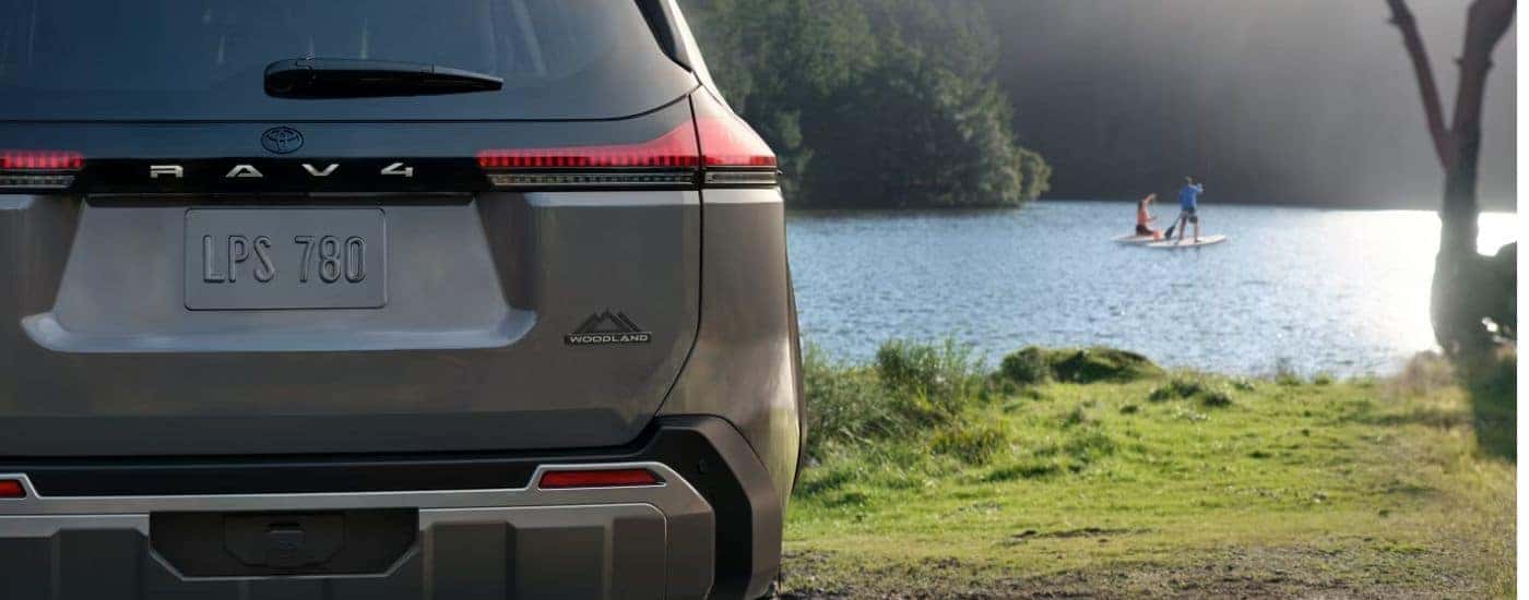 Tan 2026 Toyota RAV4 Wood Land rear view in front of a lake.