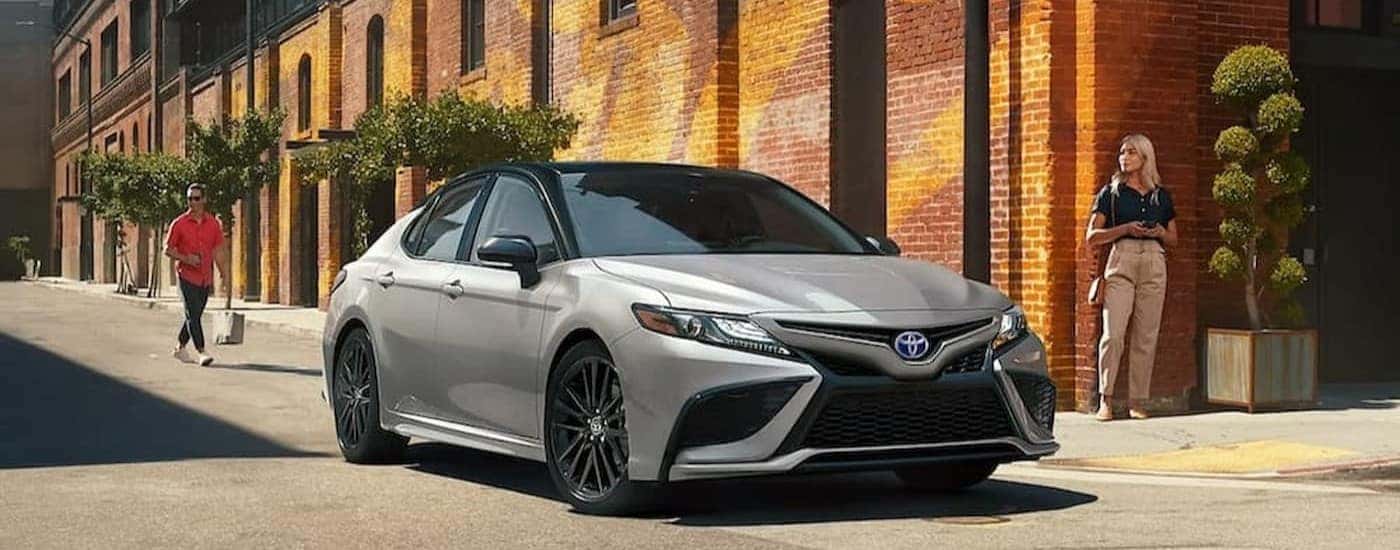 A silver 2023 Toyota Camry driving in a city.