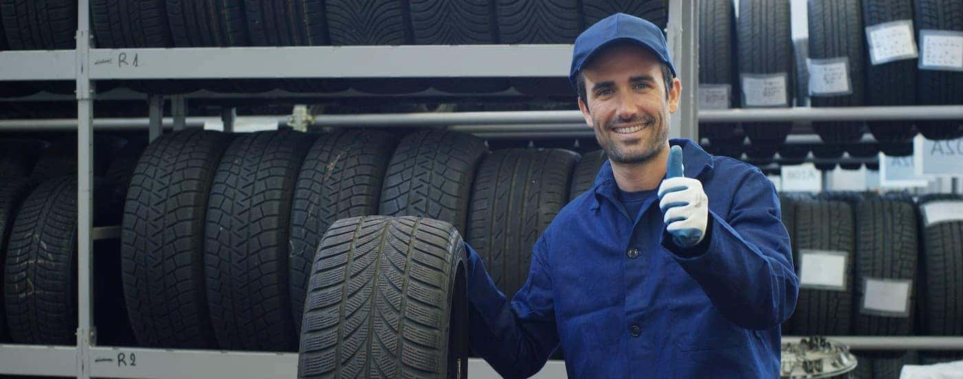 A technician giving a thumbs up while holding a tire.
