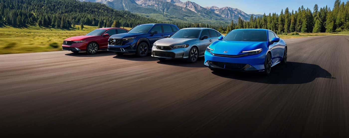 2026 Honda Hybrid Family vehicles shown in a three-quarter view, driving on a road with mountains in the background.