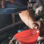 Male adding oil with a funnel