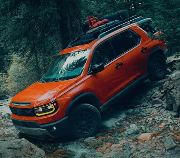 Orange 2026 Honda Passport offroading on hill with rocks