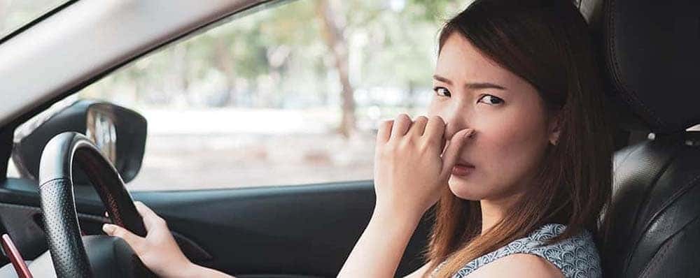 Girl holding her nose inside smelly car
